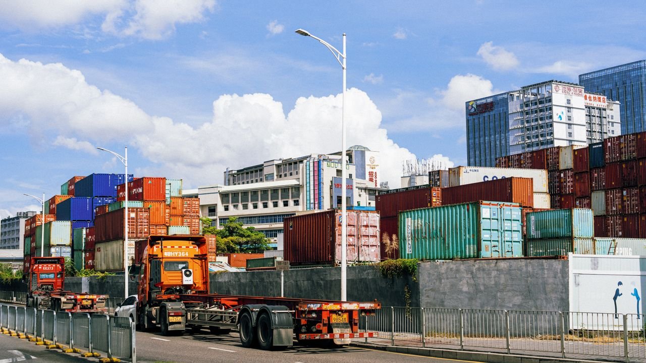 Colorful shipping containers stack at an industrial port under clear skies.